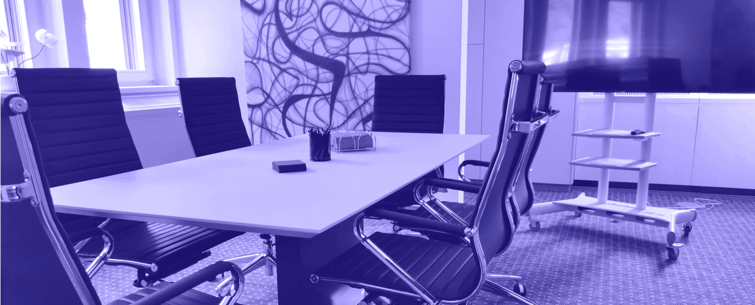 A sleek, modern conference room with black leather office chairs around a white rectangular table. The room features abstract wall art, a large screen on a stand, and a minimalist, professional atmosphere. Office supplies, such as pens and notebooks, are placed on the table, suggesting a meeting space ready for business discussions.